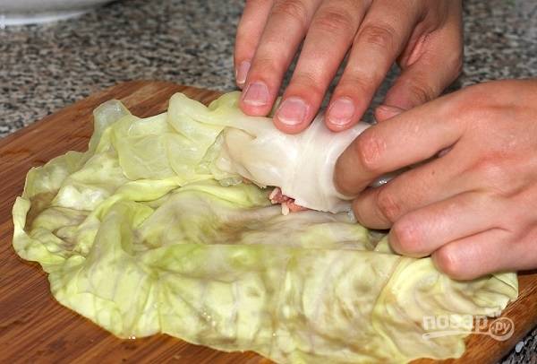 6. Возьмите листочек капусты, выложите на край начинку и аккуратно заверните. 