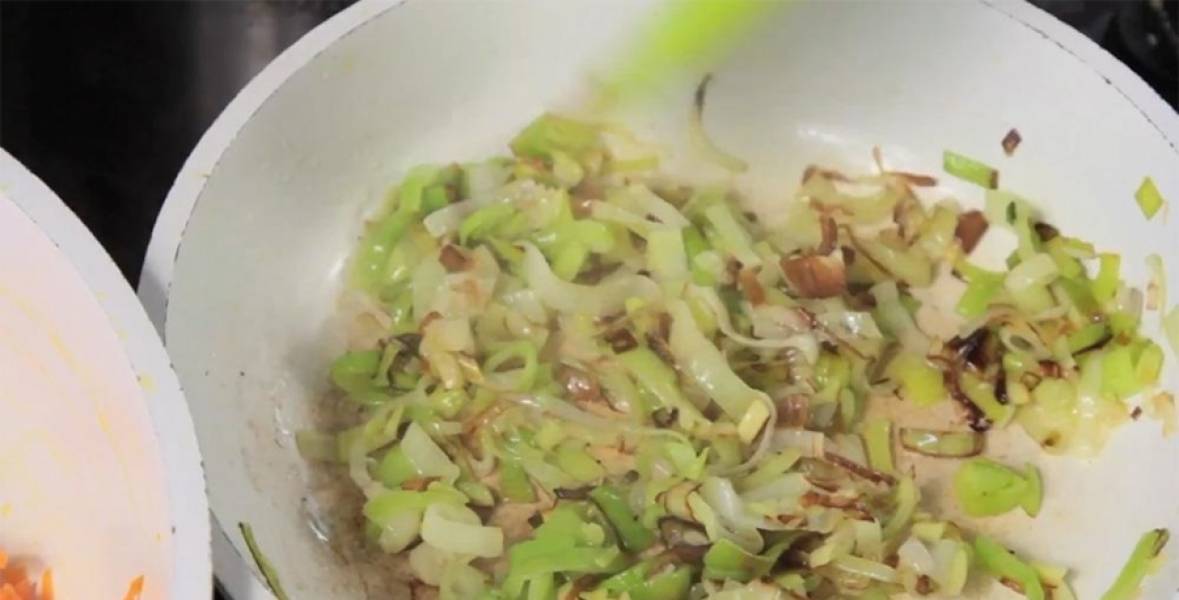 Нарежьте лук-порей полукольцами: вам понадобится только его "белая" часть. Так же, как и морковь, обжарьте лук на сковороде. 