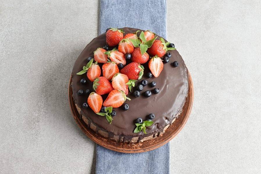 Растопите шоколад на водяной бане и быстро полейте охлажденный торт. Аккуратно выложите сверху свежие ягоды. Украсьте торт мятой или по своему желанию.