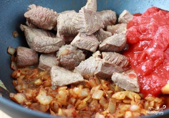 В чашу с овощами добавьте заранее обжаренное свиное мясо. Вылейте банку томатов в собственном соку. Перемешайте ингредиенты и дождитесь, пока томаты начнут закипать.