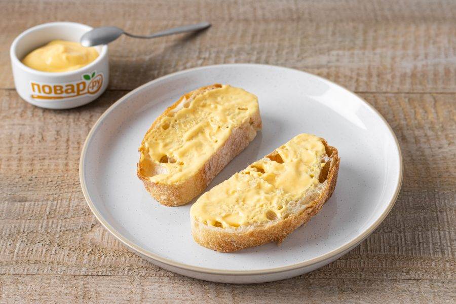 Ломтики хлеба смажьте сырным соусом.