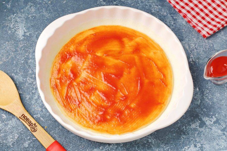 Поставьте форму в разогретую до 180 градусов духовку буквально на пару минут, чтобы тесто схватилось. Затем форму вытащите и смажьте основу любым томатным соусом.