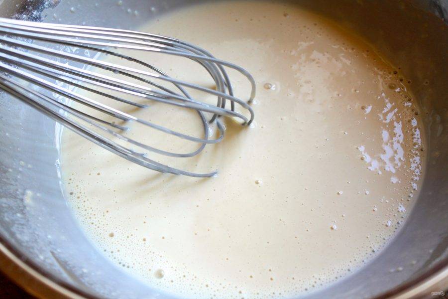 Влейте в муку половину молока и хорошо вымешайте тесто венчиком. Оставшуюся часть молока соедините с лимончелло и перемешайте тесто. 