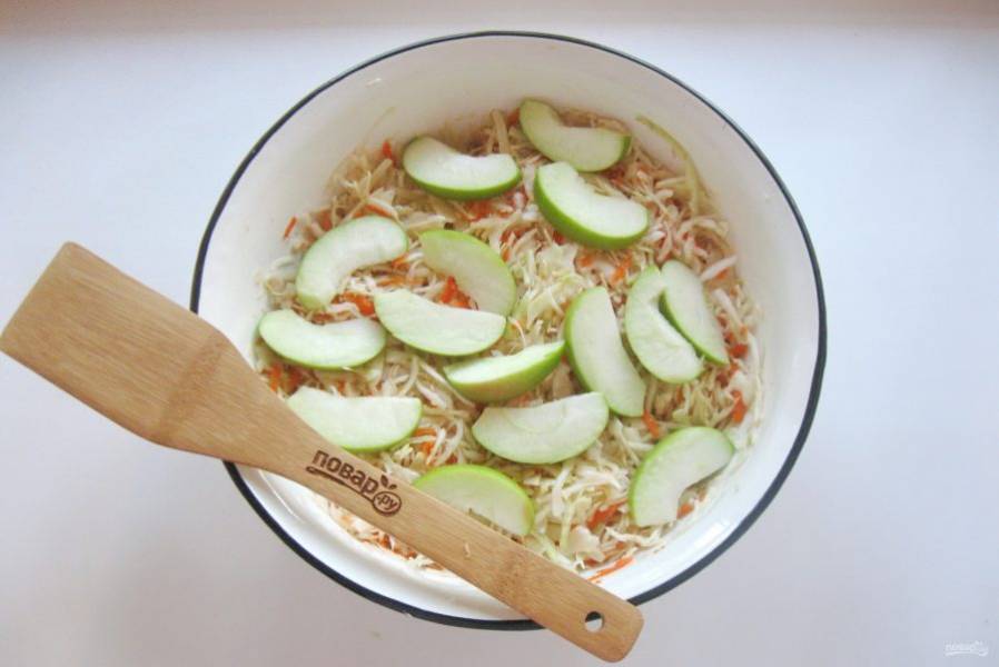 Яблоки помойте, удалите семена и нарежьте тонкими дольками. Выложите в миску с капустой и перемешайте.