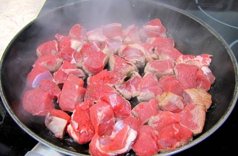 Первым делом мы промываем баранину и нарезаем ее кубиками с шириной в 2 см, выкладываем мясо на бумажное полотенце, чтобы оно подсохло. Ставим сковороду на сильный огонь и разогреваем в ней растительное мясо. Обжариваем баранину на сольном огне (мясо должно лежать в один слой) до золотистой корочки.