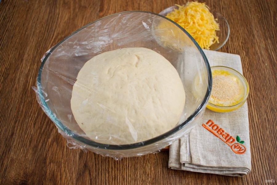 Замесите тесто слегка липнущее к рукам. Поместите тесто в миску, смазанную маслом. Накройте пищевой пленкой, поставьте в теплое место на 1 час для подъема.