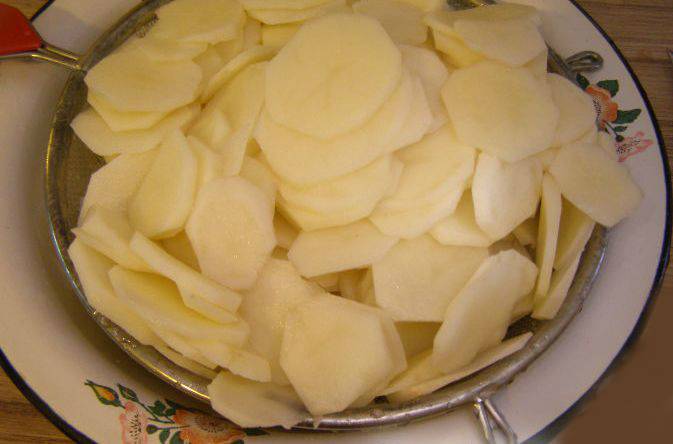 1. Картофель тщательно промойте под проточной водой, очистите от кожуры и аккуратно нарежьте ломтиками средней толщины. Посолите картошку, разотрите её руками так, чтобы соль равномерно распределилась.