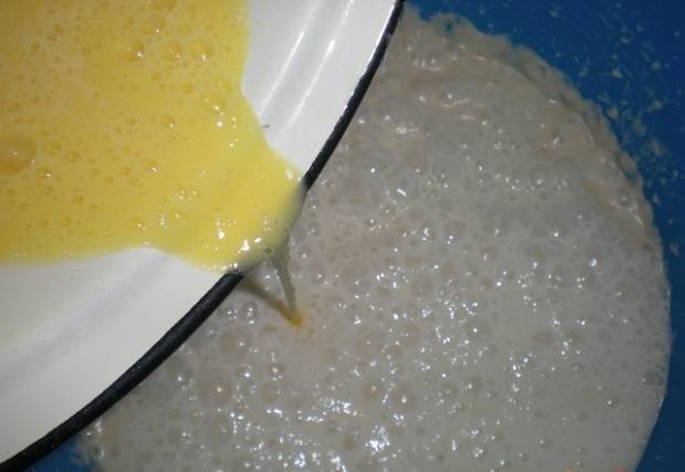 2. Взбить яйца с половиной стакана сахара до однородности. Влить тонкой струйкой в опару, когда у нее появятся пузырьки. Постоянно взбивая, всыпать просеянную муку и сделать густое тесто. Затем постепенно вливать тонкой струйкой молоко, разводя тесто до нужно консистенции. 