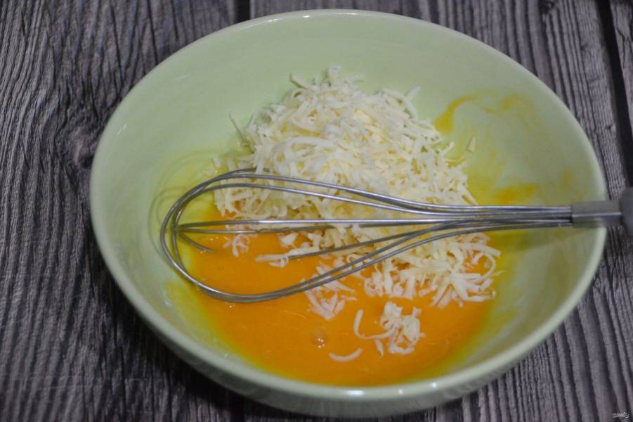 К желткам добавьте тертый сыр.