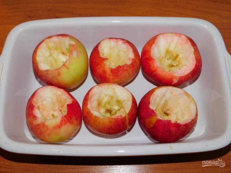 Яблоки помойте, извлеките из них сердцевину, не доходя до дна. Выложите подготовленные яблоки в форму для запекания.