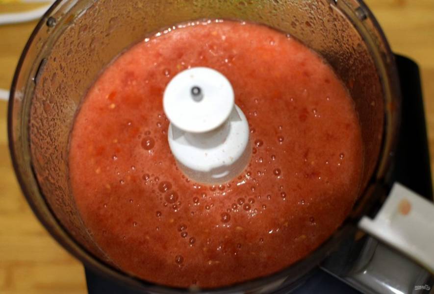 Пробейте блендером спелые помидоры. Добавьте к овощам, доведите до кипения. Убавьте огонь ниже среднего, всыпьте соль и сахар, и тушите, помешивая, без крышки до выпаривания жидкости от помидор. Свободная жидкость должна испариться и на поверхности икры будет окрашенное масло. Ближе к концу добавьте рубленный чеснок.