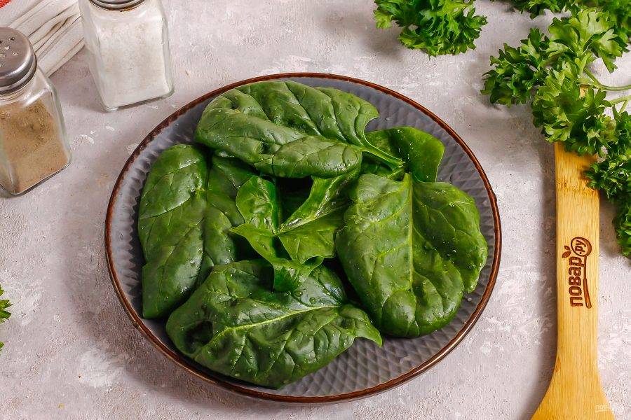 Промойте листья шпината, стряхните лишнюю влагу с них и выложите их на тарелку. 