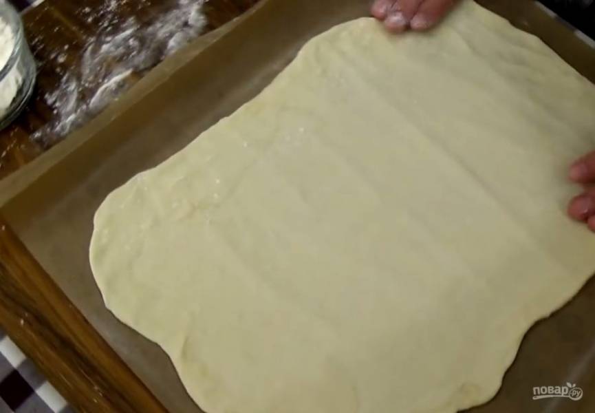 3. Разделите тесто на две части и раскатайте в тонкий пласт. При помощи скалки перенесите пласт на бумагу для выпечки и дайте постоять при комнатной температуре 10 минут. 
