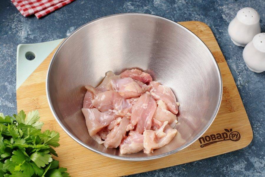 Куриные бёдрышки разделайте, отделив мясо от костей, нарежьте кусочками и переложите в глубокую миску.