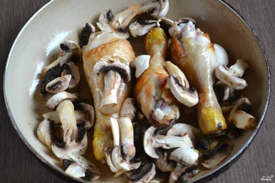Добавьте грибы к обжаренной курице, также всыпьте соль и специи, жарьте 8-10 минут.