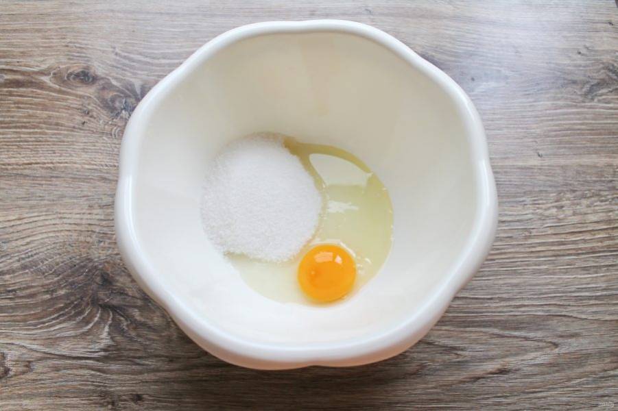 В миску разбейте яйцо, добавьте сахар.
