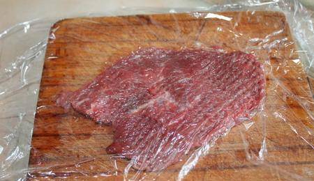 Мясо нарежьте тонкими пластинками, а затем отбейте с двух сторон, предварительно накрыв пищевой пленкой.