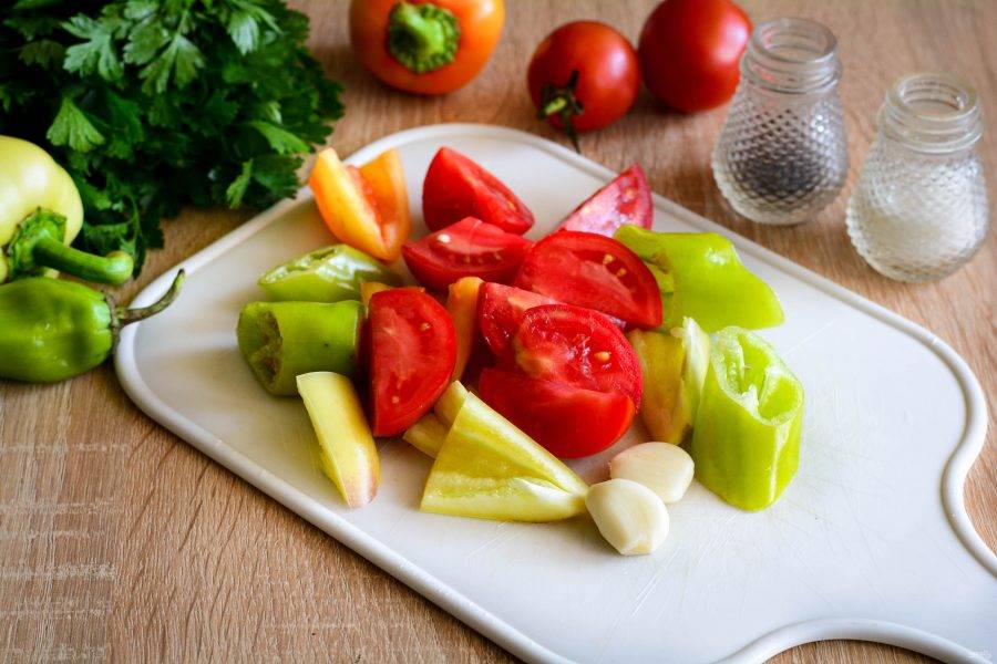 Чеснок и сладкий перец почистите. С помидоров срежьте плодоножку, с перца чили только хвостики, семена оставьте - аджика получится более острой. Нарежьте кусочками все овощи.