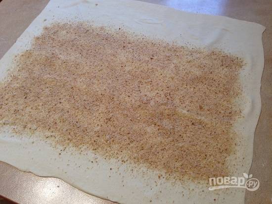 7. Раскатываем тесто в тонкий пласт, по размеру больше стандартного листа пергамента для выпечки. И посыпаем ровным слоем сухарей, отступая с одного края примерно на 5-6 см, а с боков — около 2 см.