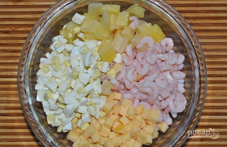Нарежьте кубиками сыр, натрите на терке яйца, порежьте кубиками ананасы. Соберите все в салатнице, добавив креветки.