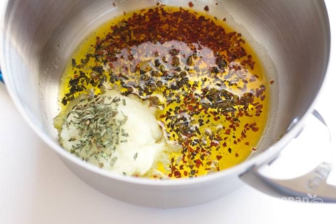 1. Разогрейте растительное масло и выложите очень мелко нарезанный лук. Добавьте базилик и орегано, по желанию можно добавить хлопья перца. Обжарьте несколько минут, помешивая. 