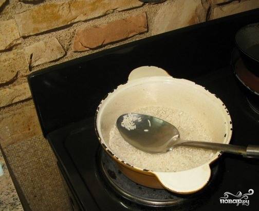 Казанок или чугунную кастрюлю поставьте на плиту и хорошенько раскалите. Всепьте в нее заранее промытый и просушенный рис и обжарьте его на сухой поверхности без масла, постоянно помешивая. На это уйдет минут десять. 
