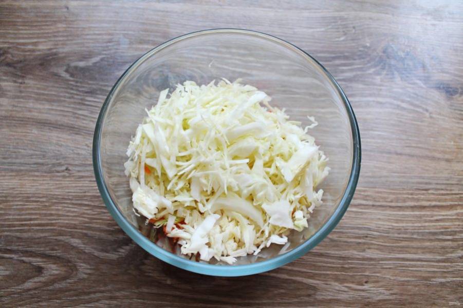 У капусты отрежьте кочерыжку и тонко нашинкуйте. Выложите ее в миску с овощами.
