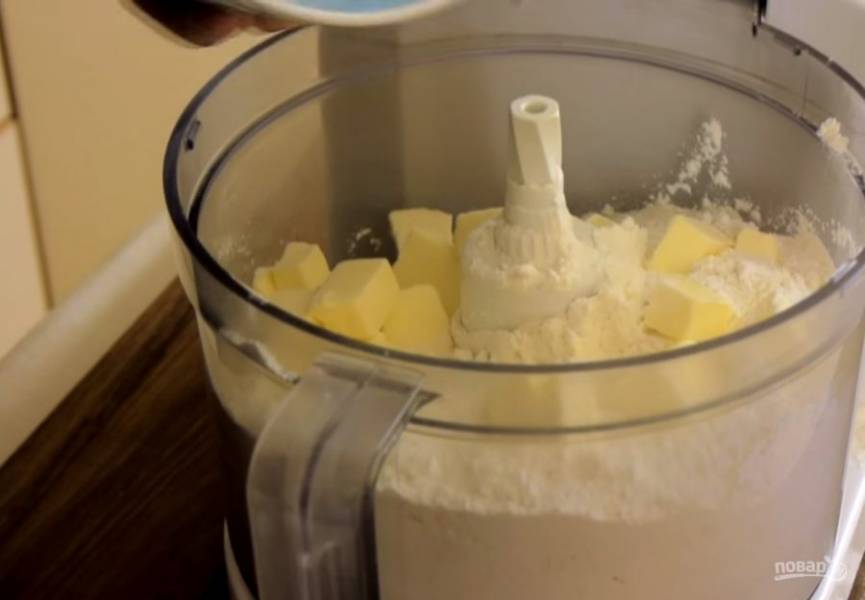 1. В чашу комбайна высыпьте охлажденную в морозилке в течение 20 минут муку, добавьте соль и охлажденное сливочное масло, нарезанное кусочками. Измельчите в крошку.