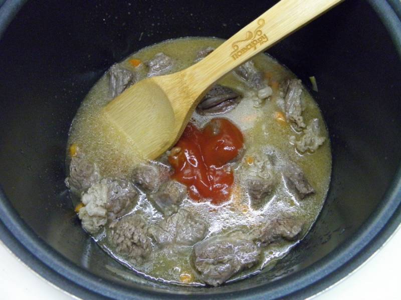 Когда мясо поменяет цвет на более светлый, влейте полтора стакана кипятка, добавьте томатный соус или пасту и перейдите в режим тушения или "Cуп" на 1 час. 