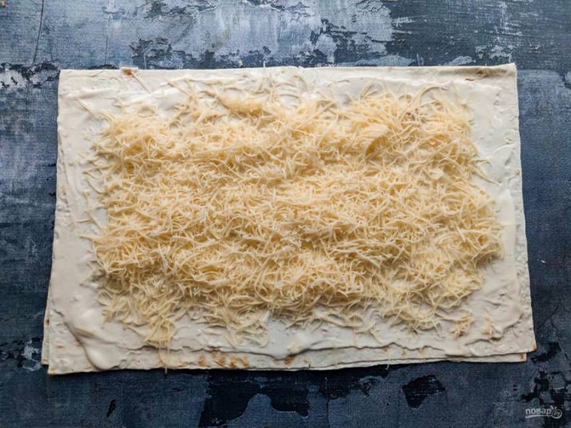 Разверните лаваш, смажьте его майонезом и выложите сыр, натертый на мелкой терке. 