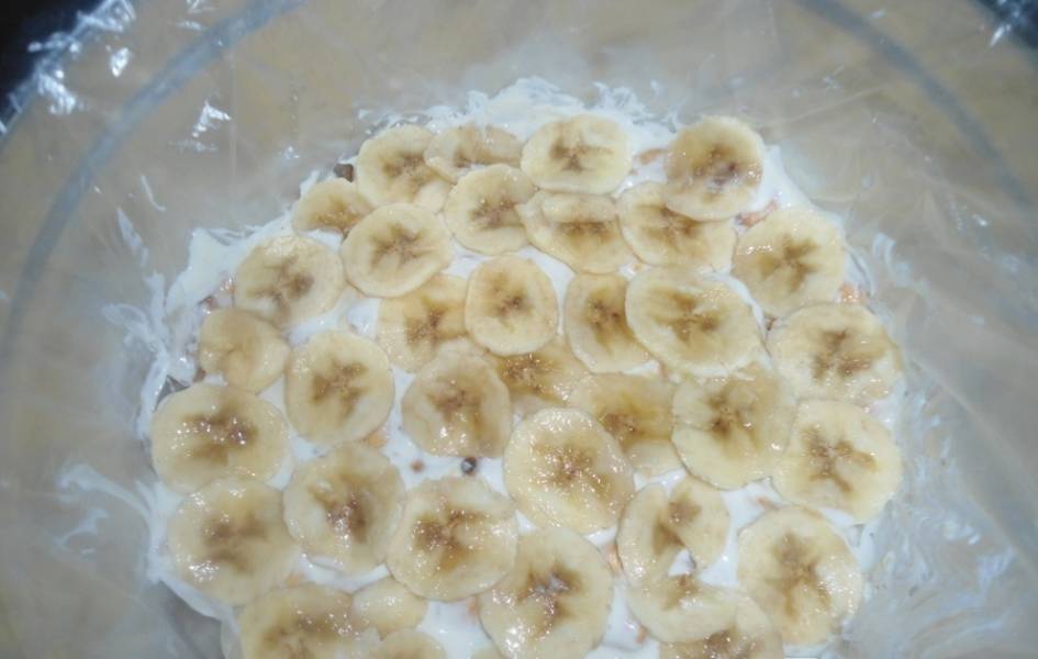 5. Теперь слой бананов. Тоже смазываем кремом, закроем края пленки, поставим форму в холодильник под пресс.