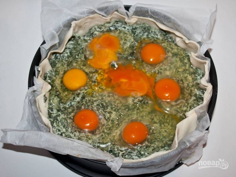 2.	Слоеное тесто раскатайте в пласт и уложите в форму для выпечки. Наколите тесто вилкой и, если используете ветчину, то положите ее на тесто. Теперь выложите половину начинки из шпината, сделайте в ней углубления для яиц. Вбейте яйца так, чтобы желтки остались целыми.