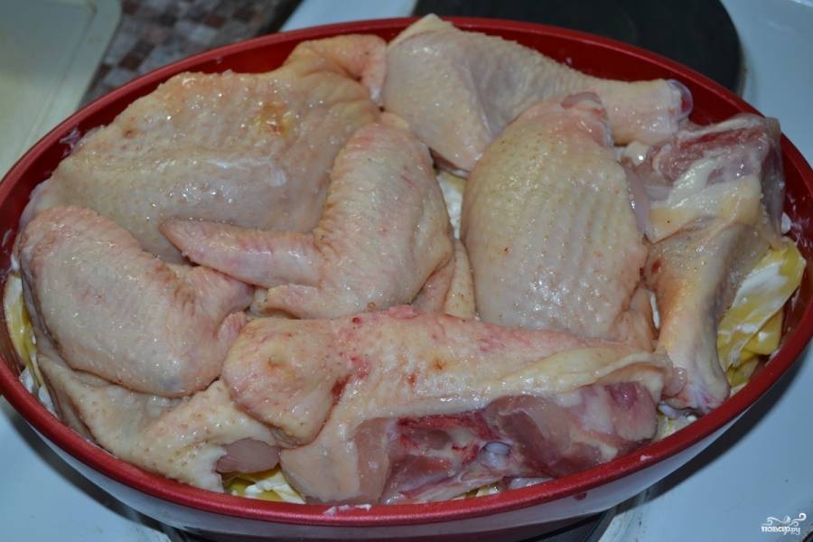 Курицу промойте и обсушите. Затем порежьте на куски (ножки я даже не режу). Выложите их поверх картошки. Рекомендую курицу посыпать приправой — получится более пикантное и ароматное блюдо. Смажьте курицу остальной сметаной.