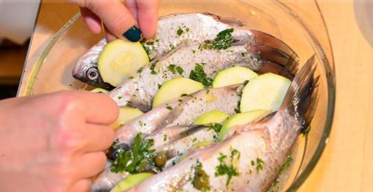 Отставьте в сторону, займитесь овощами. Порежьте колечками кабачок, лук, помидоры разрежьте на половинки. Затем выложите рыбу в форму для запекания, прослоите ее овощами.