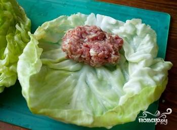 Готовим начинку. В мясной фарш выдавливаем чеснок, также солим его и перчим. Варим рис до полуготовности. Смешиваем его с фаршем. Лепим из фарша котлету, и заворачиваем её в лист капусты.
