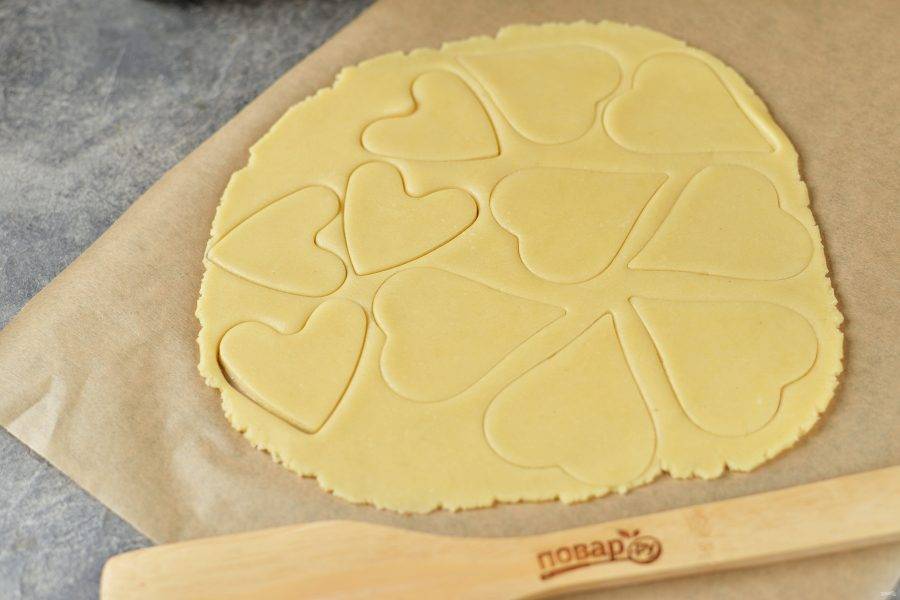 Раскатайте белое тесто до толщины 3 миллиметра, проще всего это делать между двух листов пергамента. Вырубкой для печенья в виде сердца вырежьте заготовки. Размер сердечек выбирайте по своему желанию. 