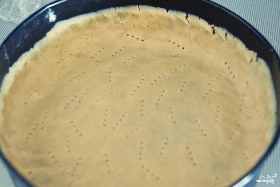 Тесто достаем из холодильника, раскатываем из него большую лепешку. Берем форму для выпекания (диаметр - около 25 см), смазываем сливочным маслом, выкладываем в него тесто. Вилкой делаем небольшие дырочки в тесте.