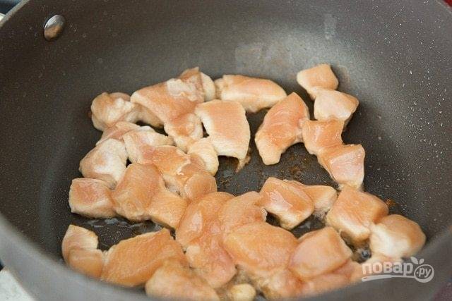 3. Затем в большой сковороде разогрейте масло. Обжарьте в нём кусочки курицы в течение 1-2-х минут с каждой стороны.