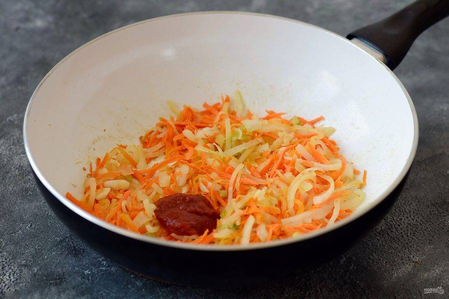 Морковь и репчатый лук тонко нашинкуйте. Разогрейте в кастрюле масло, добавьте томатную пасту и обжарьте лук с морковью до мягкости. Добавьте измельченный чеснок.