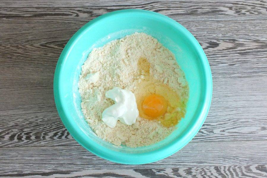 В масляно-мучную крошку добавьте сметану, яйцо. Замесите тесто.