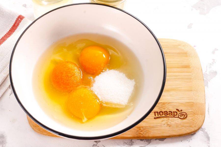 Вбейте куриные яйца в глубокую емкость, всыпьте туда же сахарный песок и соль. Соль добавлять обязательно — она подчеркивает сладость выпечки.