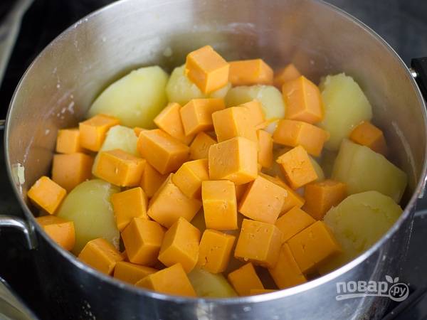 1. Картофель очистите и отварите в подсоленной воде до готовности. Воду слейте, сразу же добавьте в кастрюлю нарезанный мелкими кубиками сыр. Накройте крышкой и оставьте минут на 5. 