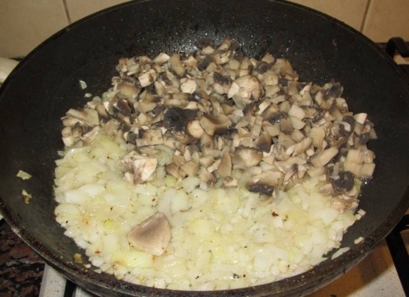 В сковороду наливаем растительное масло и обжариваем на нем нарезанный мелко лук до золотистого цвета, затем выкладываем к нему грибы. 