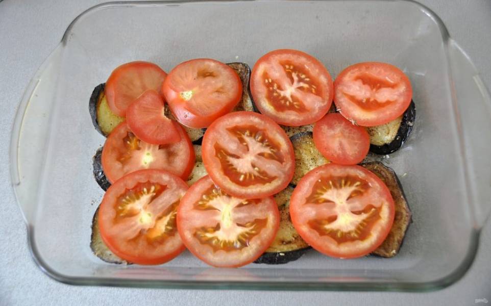 Выложите слой помидоров, нарезанных кружочками.