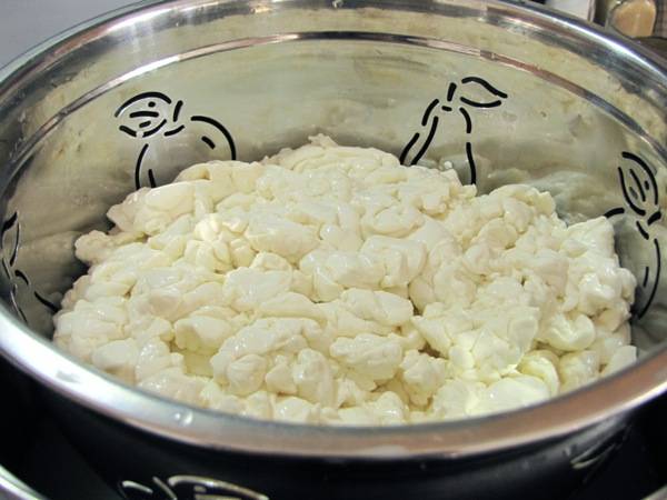 3. Массу небольшими порциями нужно переложить в дуршлаг и дать стечь сыворотке. Сырные сгустки можно поместить в марлю, сложенную в несколько раз, и повесить на раковиной, например. 