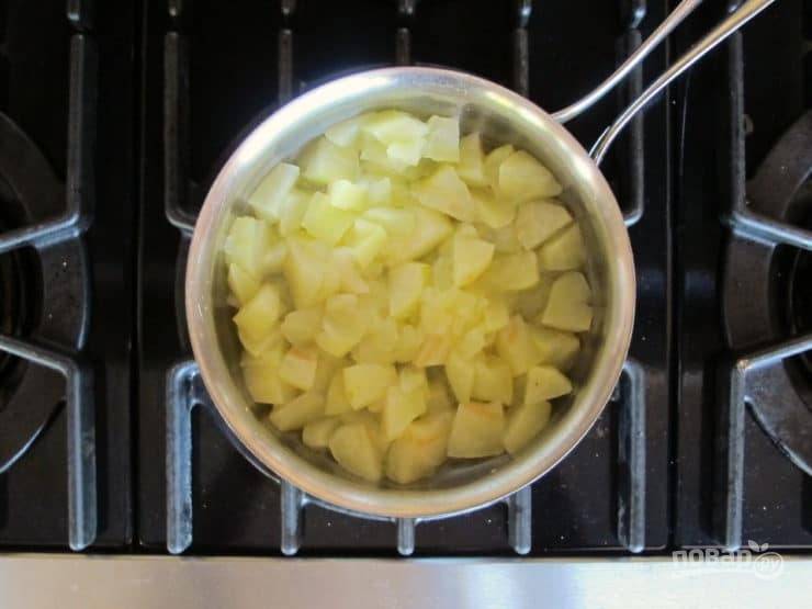 1. Подготовьте начинку. Яблоки почистите и нашинкуйте кубиками. Выложите их в сотейник и влейте воду. Проварите фрукты пару минут до мягкости.