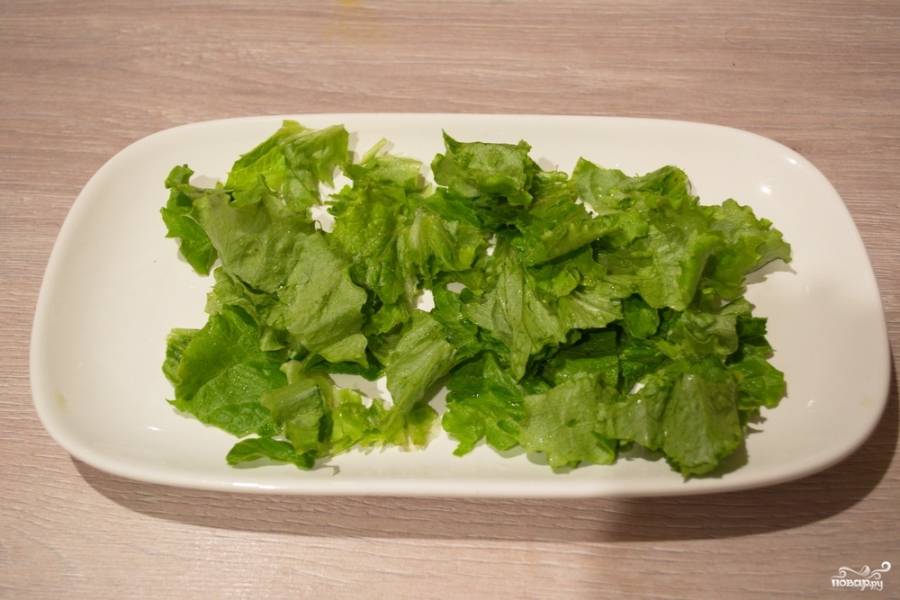 Салатные листья нужно вымыть и нарвать руками. Уложите их на блюдо.