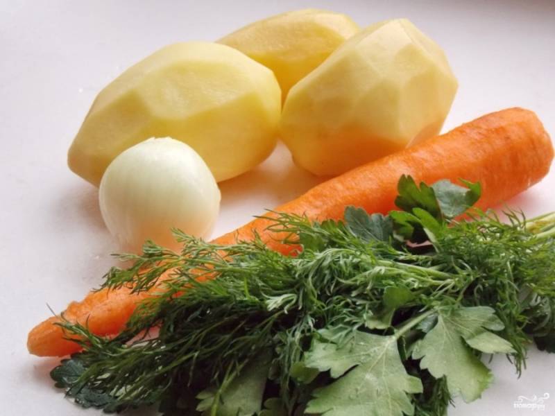 Пока тесто настаивается, снова займитесь бульоном. Подготовьте овощи: почистите картошку, морковку, лук. Порежьте картошку кубиками, морковку — колечками, лук — мелкими кубиками. Зелень тоже мелко порежьте. 