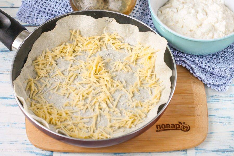 Натрите твердый сыр на терке с мелкими ячейками и присыпьте первый слой.
