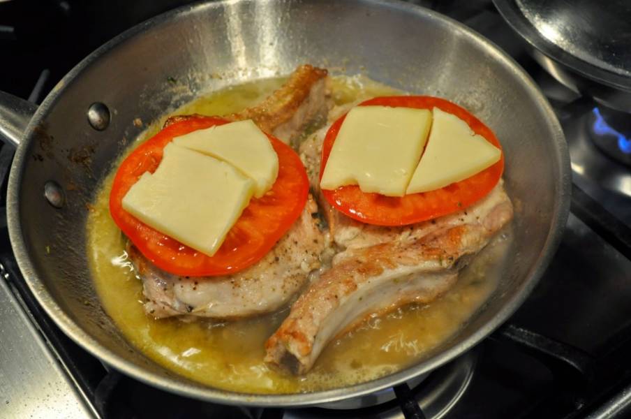 7. Выложить сверху мяса помидор, подсолить по вкусу и накрыть ломтиком сыра. Теперь огонь можно уменьшить и довести мясо до готовности. 